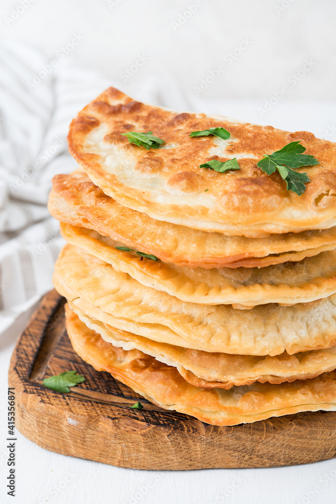 Homemade fried empanadas with pork, chebureks with mushrooms on a wooden board Homemade fried empanadas with pork, chebureks with mushrooms on a wooden board