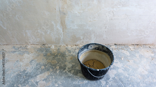 black bucket for plaster on the background of a white wall. repairs
