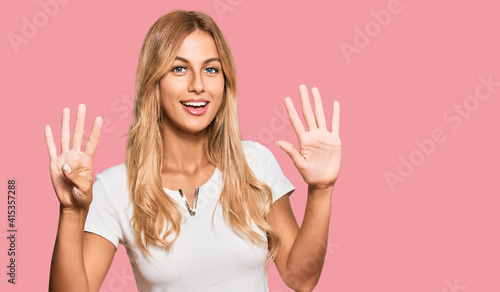 Beautiful blonde young woman wearing casual white tshirt showing and pointing up with fingers number nine while smiling confident and happy.