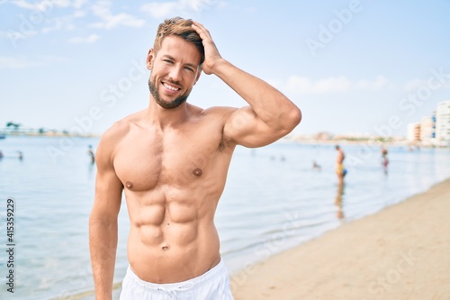 Handsome fitness caucasian man at the beach on a sunny day showing muscular fitness body