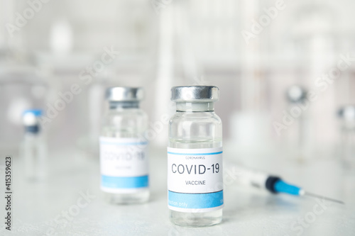 Vials and syringe with coronavirus vaccine on light table