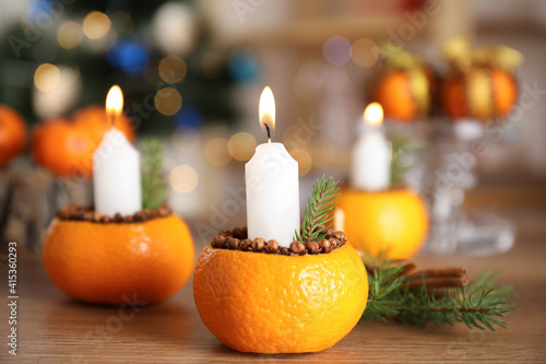 Burning candle in tangerine peel as holder on wooden table