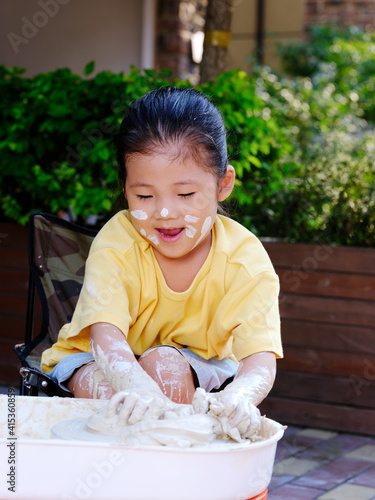 A lovely child is doing pottery outdoors
