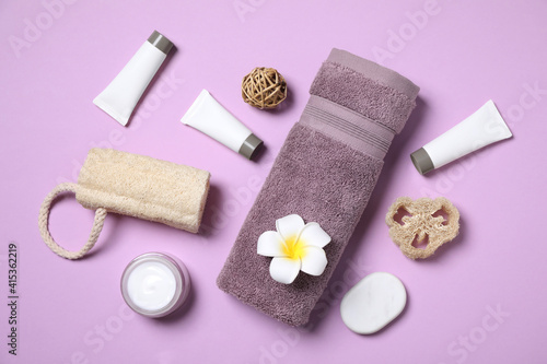 Flat lay composition with different cosmetic products and flower on lilac background