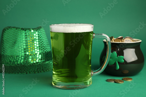 Glass of beer, gold and party hat on green background. St Patrick's Day celebration