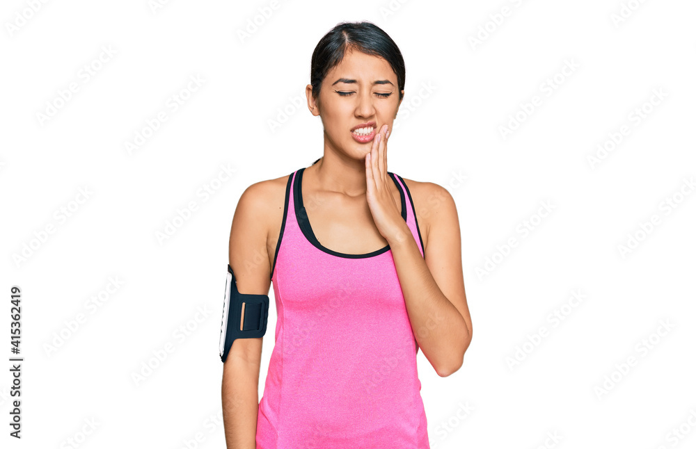 Beautiful asian young sport woman wearing sportswear and arm band touching mouth with hand with painful expression because of toothache or dental illness on teeth. dentist Beautiful asian young sport woman wearing sportswear and arm band touching mouth with hand with painful expression because of toothache or dental illness on teeth. dentist