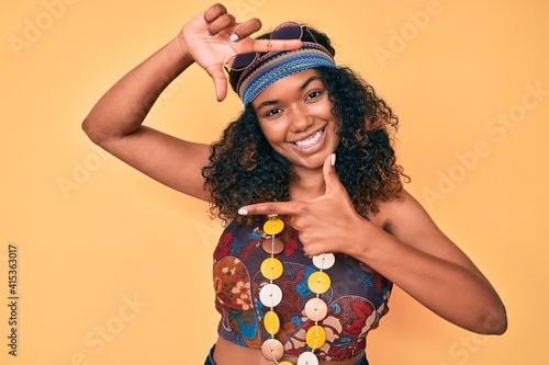 Young african american woman wearing bohemian and hippie style smiling making frame with hands and fingers with happy face. creativity and photography concept.
