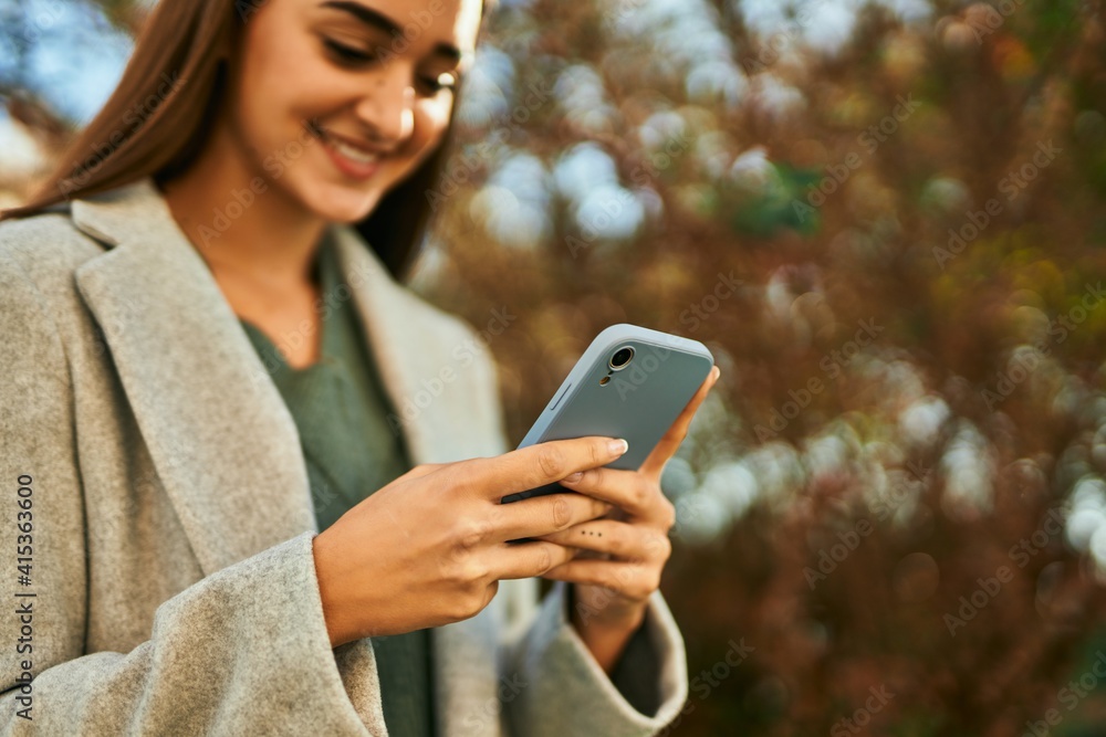Young hispanic girl smiling happy using smartphone at the city. Young hispanic girl smiling happy using smartphone at the city.