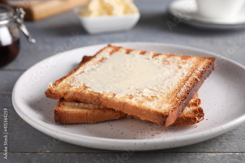 Tasty toasts with butter served on grey wooden table, closeup