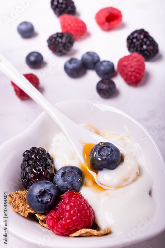 in the heart-shaped bowl ingredients for a healthy breakfast based on: white yogurt, fresh berries and multigrain flakes