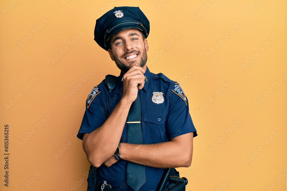 Handsome hispanic man wearing police uniform looking confident at the camera smiling with crossed arms and hand raised on chin. thinking positive. Handsome hispanic man wearing police uniform looking confident at the camera smiling with crossed arms and hand raised on chin. thinking positive.