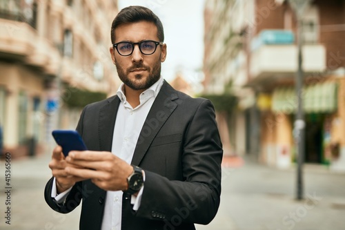 Young hispanic businessman with serious expression using smartphone at the city.