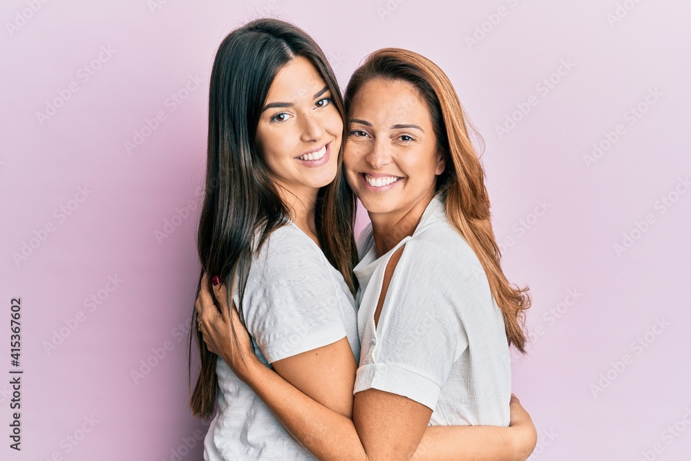 Beautiful hispanic mother and daughter smiling happy hugging over isolated pink background. - obrazy, fototapety, plakaty 