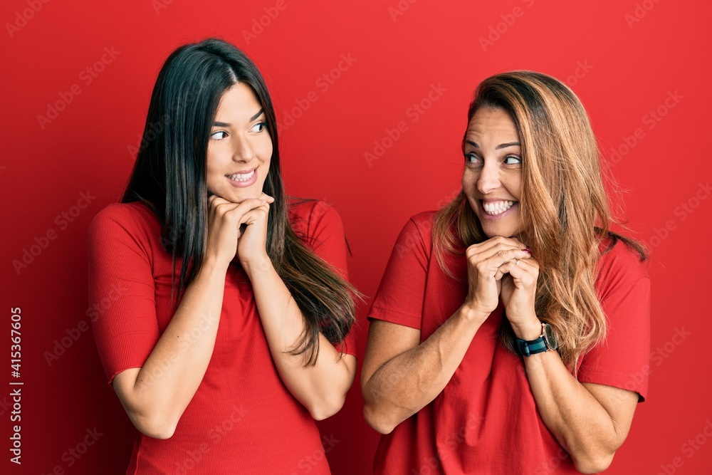 Hispanic family of mother and daughter wearing casual clothes over red background laughing nervous and excited with hands on chin looking to the side Hispanic family of mother and daughter wearing casual clothes over red background laughing nervous and excited with hands on chin looking to the side