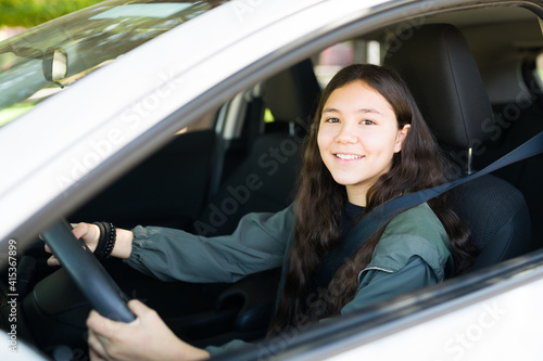 Excited teen girl laughing while driving a new car