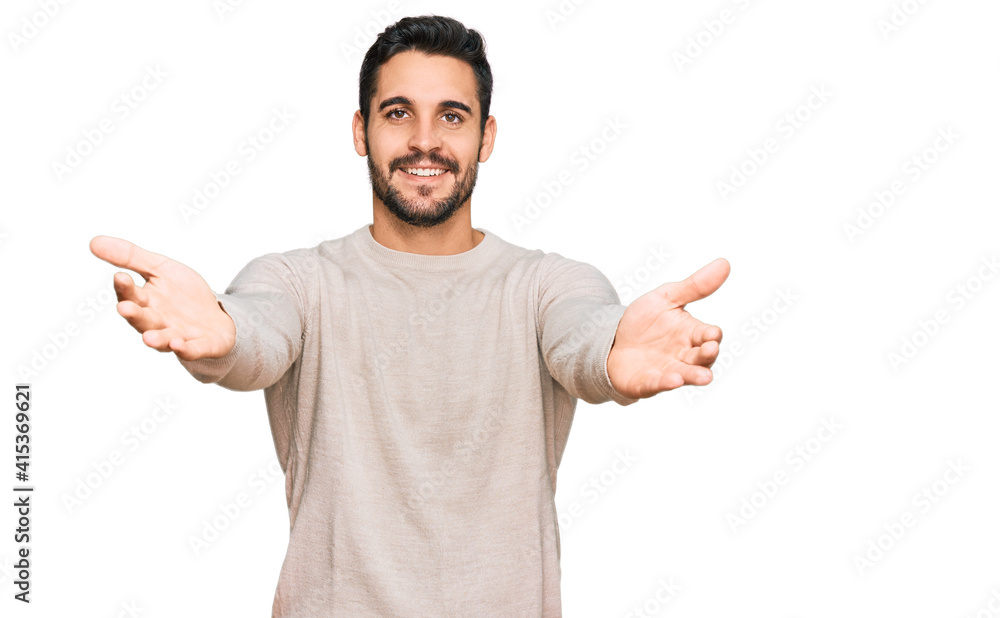 Young hispanic man wearing casual clothes looking at the camera smiling with open arms for hug. cheerful expression embracing happiness. Young hispanic man wearing casual clothes looking at the camera smiling with open arms for hug. cheerful expression embracing happiness.