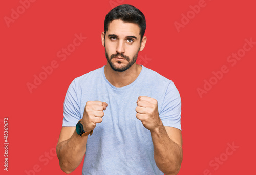 Young hispanic man wearing casual clothes ready to fight with fist defense gesture, angry and upset face, afraid of problem