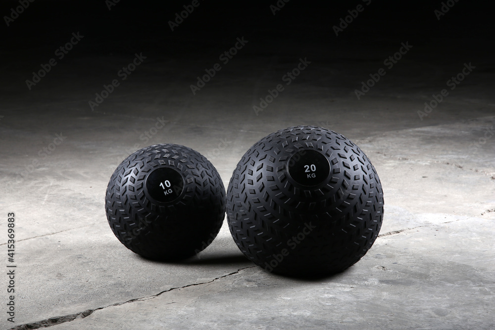Weighted slam balls at gym on the ground, with nobody. Dark background. Weighted slam balls at gym on the ground, with nobody. Dark background.