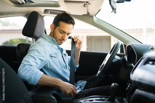 Male driver behind the wheel putting on his seatbelt