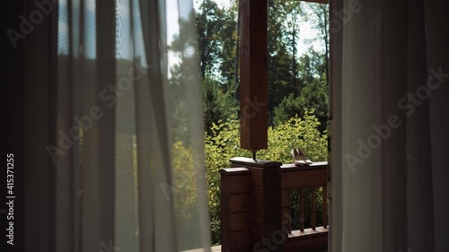 View from the house to the veranda through the open door. There are shoes on the porch railing. Wedding frame. High quality FullHD footage