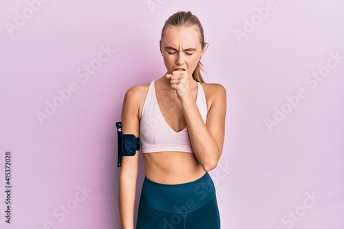 Beautiful blonde woman wearing sportswear and arm band feeling unwell and coughing as symptom for cold or bronchitis. health care concept. © Krakenimages.com