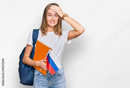 Beautiful young blonde woman exchange student holding russian flag stressed and frustrated with hand on head, surprised and angry face