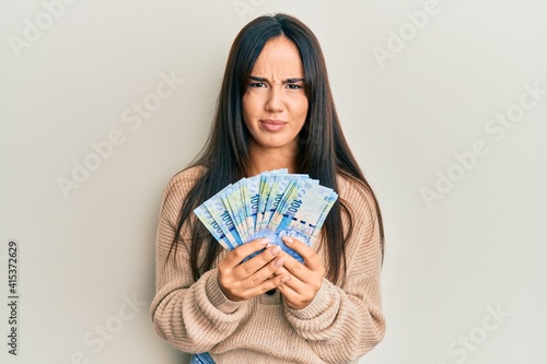 Young beautiful hispanic girl holding south african 100 rand banknotes skeptic and nervous, frowning upset because of problem. negative person.