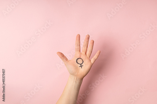 Female hand with female symbol of Venus on pink background for international womens day