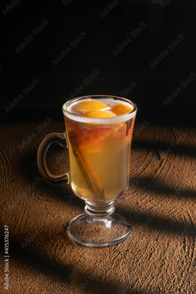 Hot fruit tea with orange, cinnamon and cloves in a clear glass Hot fruit tea with orange, cinnamon and cloves in a clear glass