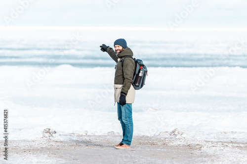 View from the back to A man standing on ice looking at a frozen sea