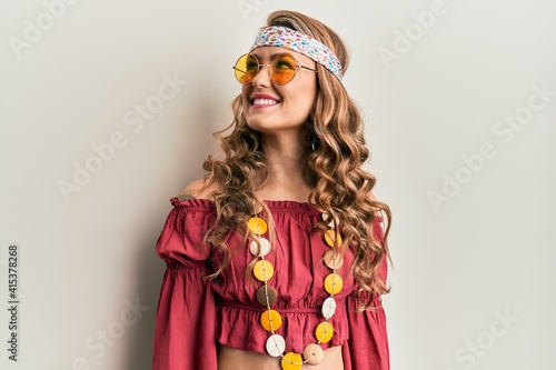 Young blonde girl wearing bohemian and hippie style looking away to side with smile on face, natural expression. laughing confident.