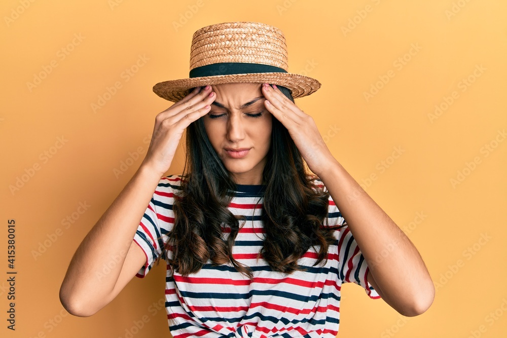Young hispanic woman wearing summer hat suffering from headache desperate and stressed because pain and migraine. hands on head. Young hispanic woman wearing summer hat suffering from headache desperate and stressed because pain and migraine. hands on head.