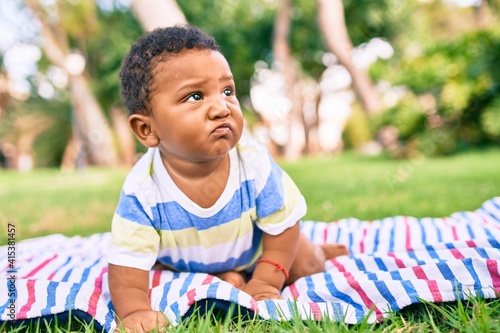 Adorable african american chubby toddler sitting on the grass at the park.