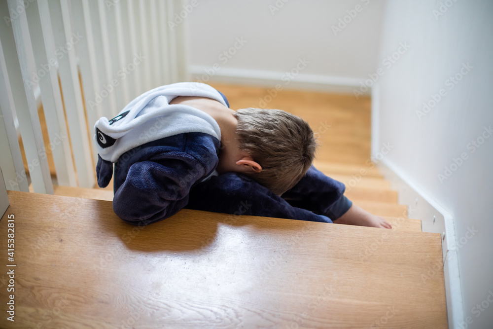 the unhappy child is sitting on the stairs with his head down the unhappy child is sitting on the stairs with his head down