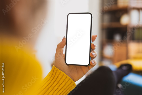 Obraz na płótnie Woman using smartphone frameless mockup blank screen in home interior