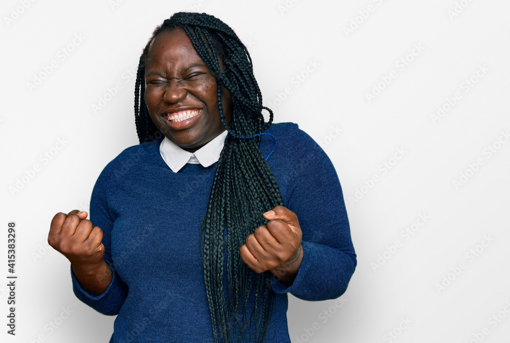 Young black woman with braids wearing casual clothes very happy and excited doing winner gesture with arms raised, smiling and screaming for success. celebration concept. Young black woman with braids wearing casual clothes very happy and excited doing winner gesture with arms raised, smiling and screaming for success. celebration concept.
