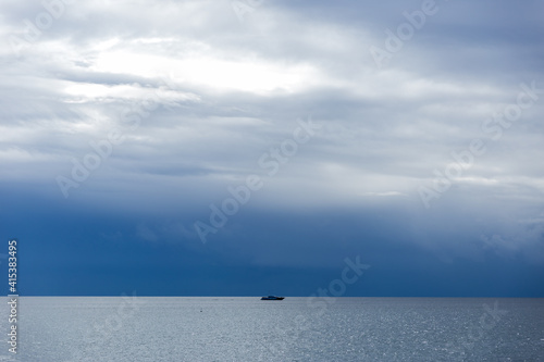 Isolated ship on Mediterranean sea. Capricious weather, storm. Shy with clouds. Scenic nature landscape. Beautiful sky colours