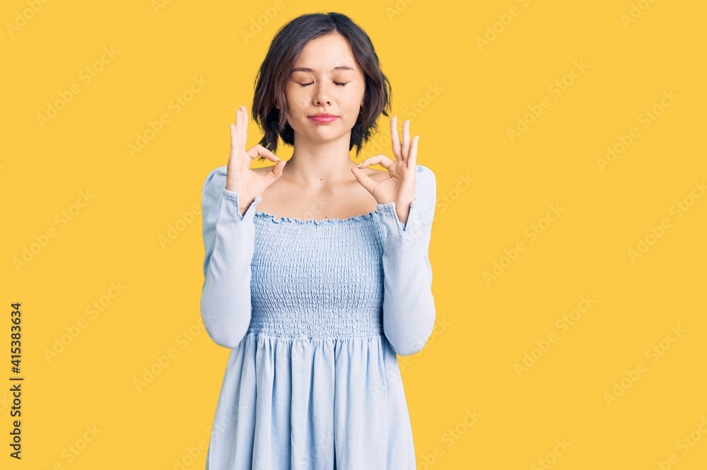 Young beautiful girl wearing casual clothes relaxed and smiling with eyes closed doing meditation gesture with fingers. yoga concept. Young beautiful girl wearing casual clothes relaxed and smiling with eyes closed doing meditation gesture with fingers. yoga concept.