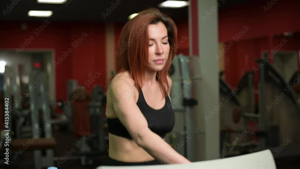 Young woman adjusts the treadmill routine for her type of workout, close-up. Young woman in the gym Young woman adjusts the treadmill routine for her type of workout, close-up. Young woman in the gym