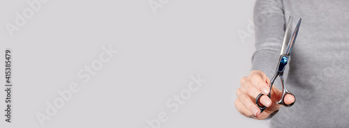Bilde på lerret Hand with thinning scissors on grey background.