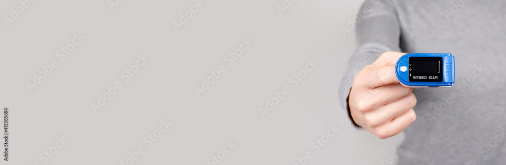 Hand with oximeter, pulse monitoring equipment on grey background. Hand with oximeter, pulse monitoring equipment on grey background.