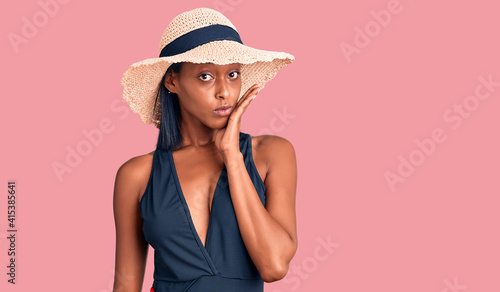 Young african american woman wearing swimsuit and summer hat thinking looking tired and bored with depression problems with crossed arms.