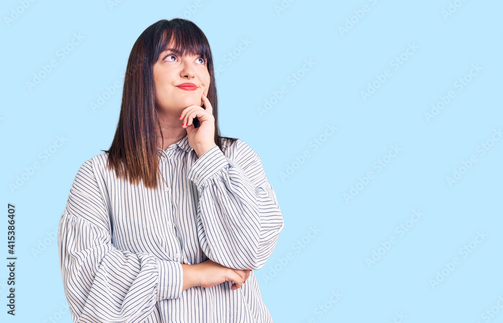Young plus size woman wearing casual clothes with hand on chin thinking about question, pensive expression. smiling with thoughtful face. doubt concept. Young plus size woman wearing casual clothes with hand on chin thinking about question, pensive expression. smiling with thoughtful face. doubt concept.