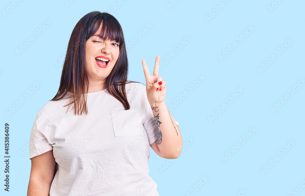 Young plus size woman wearing casual clothes smiling with happy face winking at the camera doing victory sign with fingers. number two. Young plus size woman wearing casual clothes smiling with happy face winking at the camera doing victory sign with fingers. number two.