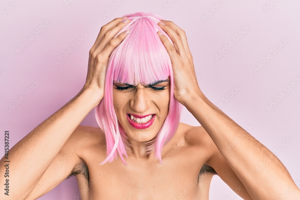 Young man wearing woman make up wearing pink wig suffering from headache desperate and stressed because pain and migraine. hands on head.