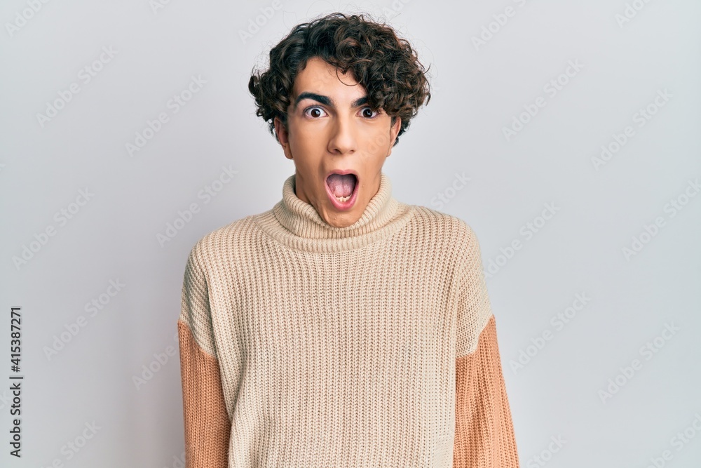 Hispanic young man wearing casual winter sweater afraid and shocked with surprise expression, fear and excited face. Hispanic young man wearing casual winter sweater afraid and shocked with surprise expression, fear and excited face.