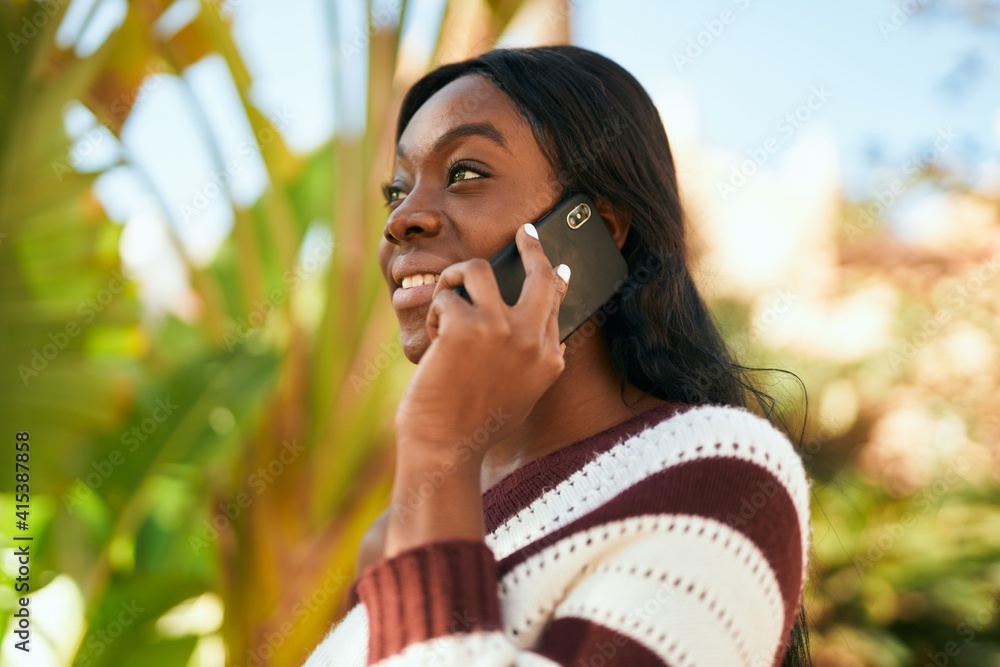 Young african american woman smiling happy talking on the smartphone at the park. Young african american woman smiling happy talking on the smartphone at the park.