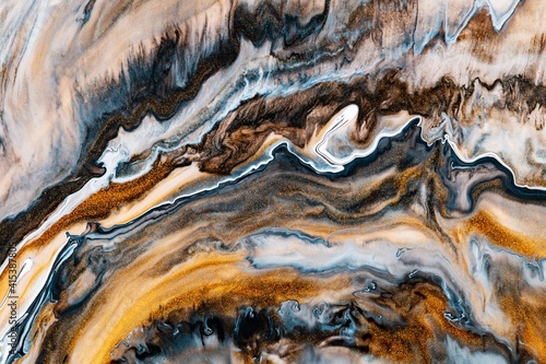 Fluid art texture. Background with abstract iridescent paint effect. Liquid acrylic picture that flows and splashes. Mixed paints for interior poster. Brown, golden and navy blue overflowing colors
