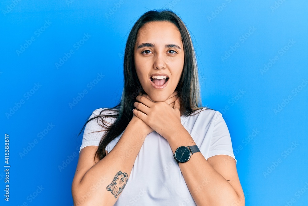 Young hispanic woman wearing casual white t shirt shouting and suffocate because painful strangle. health problem. asphyxiate and suicide concept. Young hispanic woman wearing casual white t shirt shouting and suffocate because painful strangle. health problem. asphyxiate and suicide concept.