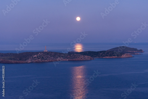 Fototapeta Naklejka Na Ścianę i Meble -  A full moon rises over the lighthouse.